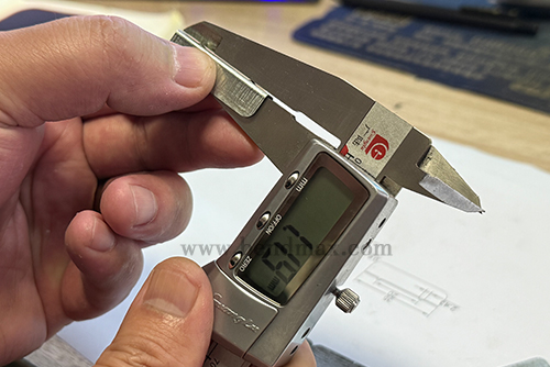 Digital caliper measuring a critical dimension of a custom metal part-4